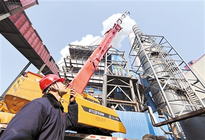 11月24日,沙河市一家玻璃生产企业的工作人员指挥吊车在脱硫塔上安装